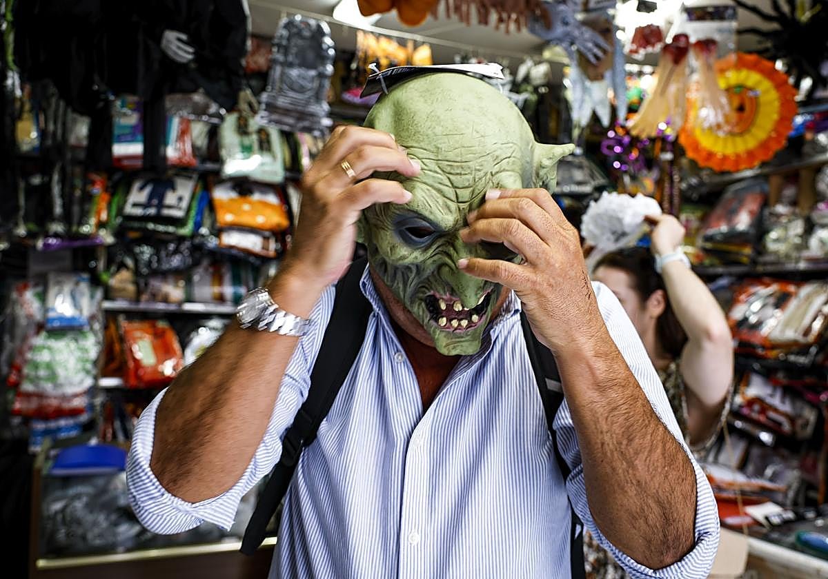 Un hombre se prueba una máscara de orco en una tienda de disfraces.