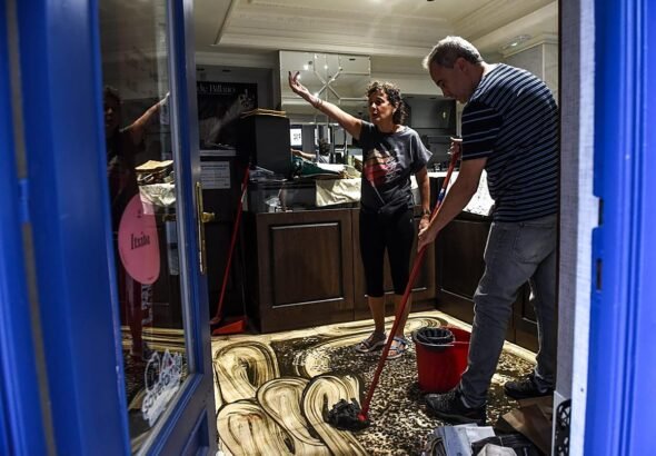 Comerciantes limpian sus locales tras la tromba de agua que anegó el Casco Viejo.