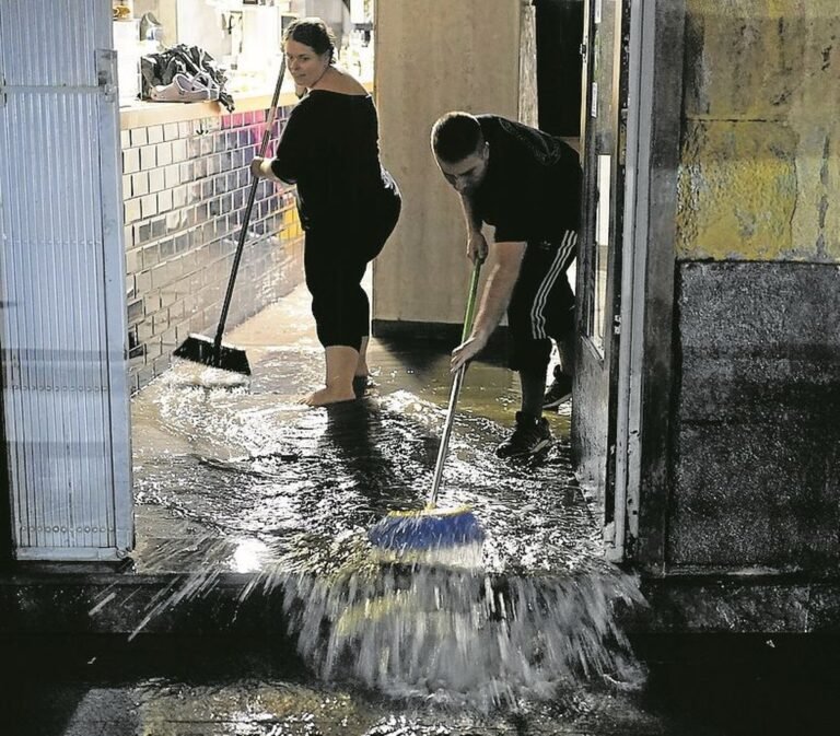 Comerciantes achican agua de su negoci.